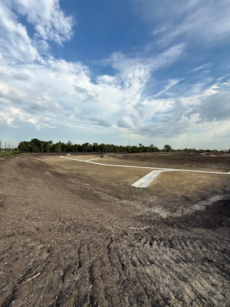 Concrete channels poured across a freshly graded site under a wide sky