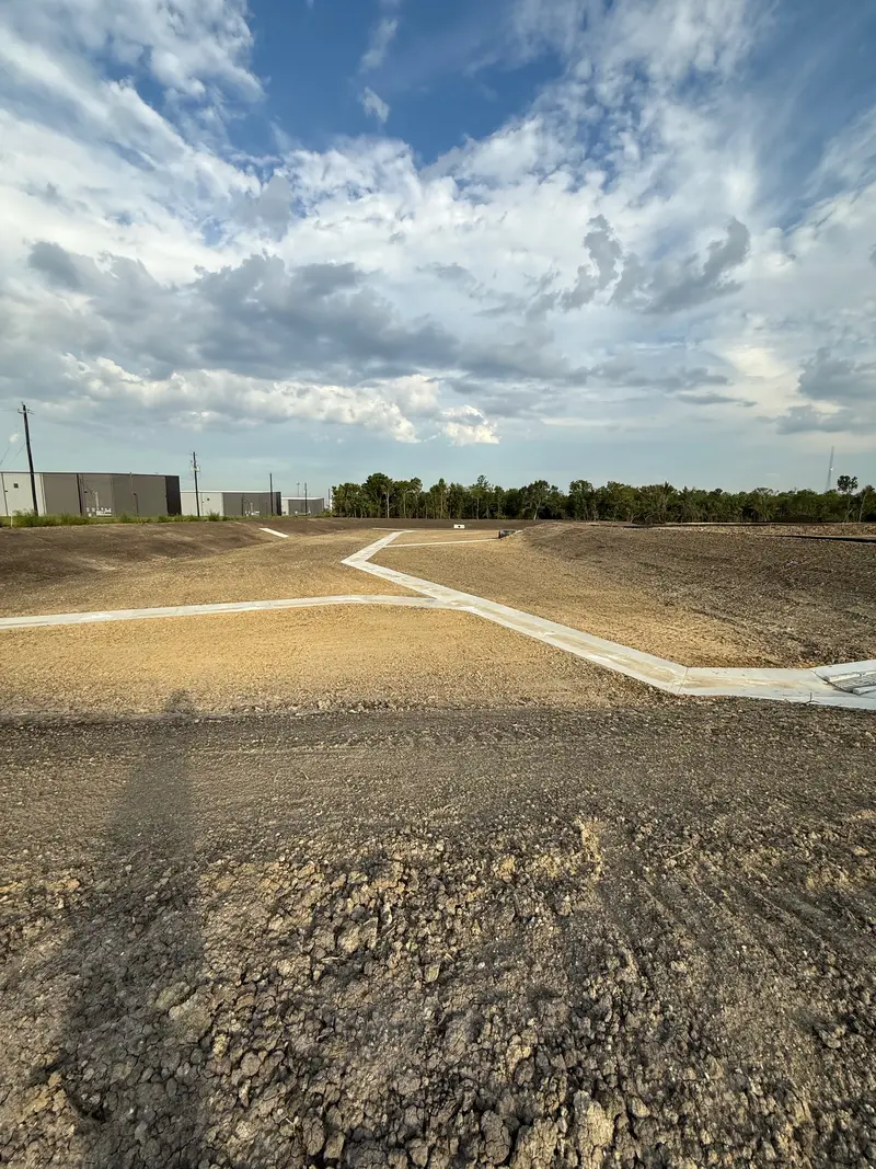 Concrete channels meeting on a graded industrial lot, warehouse buildings on the horizon