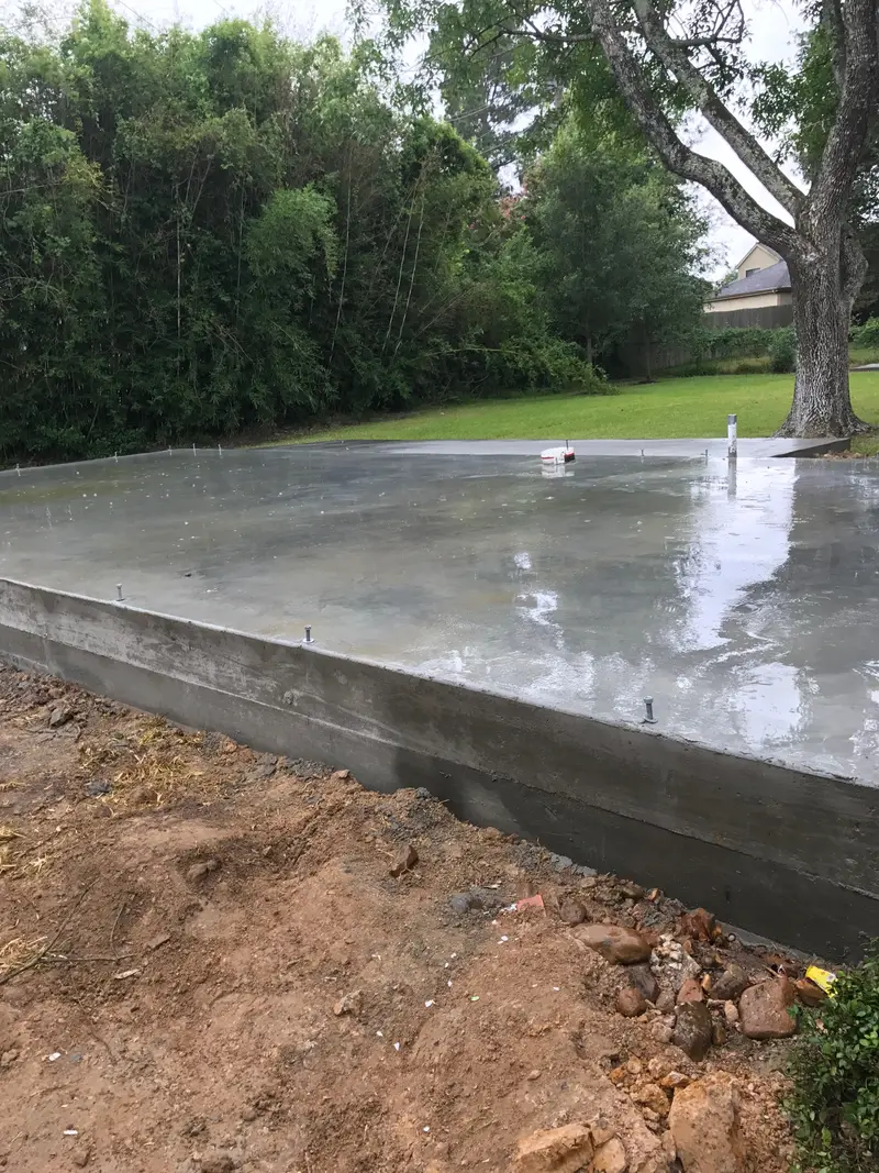 Edge of a finished concrete slab with trees and lawn in the background